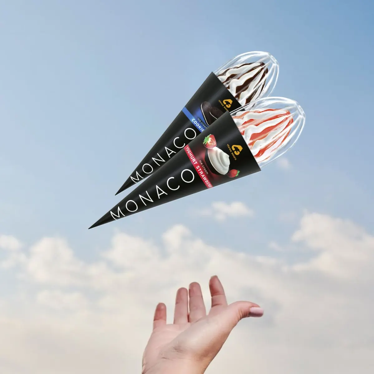 Two Monaco ice-cream cones flying across a blue sky towards an open hand